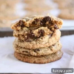Stack of soft and chewy oatmeal chocolate chip coconut cookies with the top one broken in half.