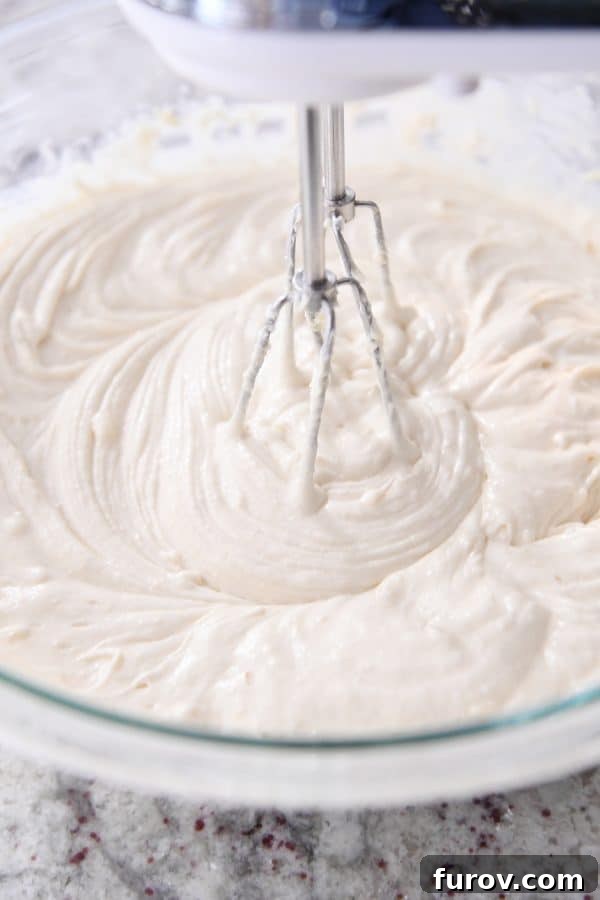 Close-up shot of chocolate chip cake batter being mixed to perfection with a handheld electric mixer, showcasing its smooth texture.