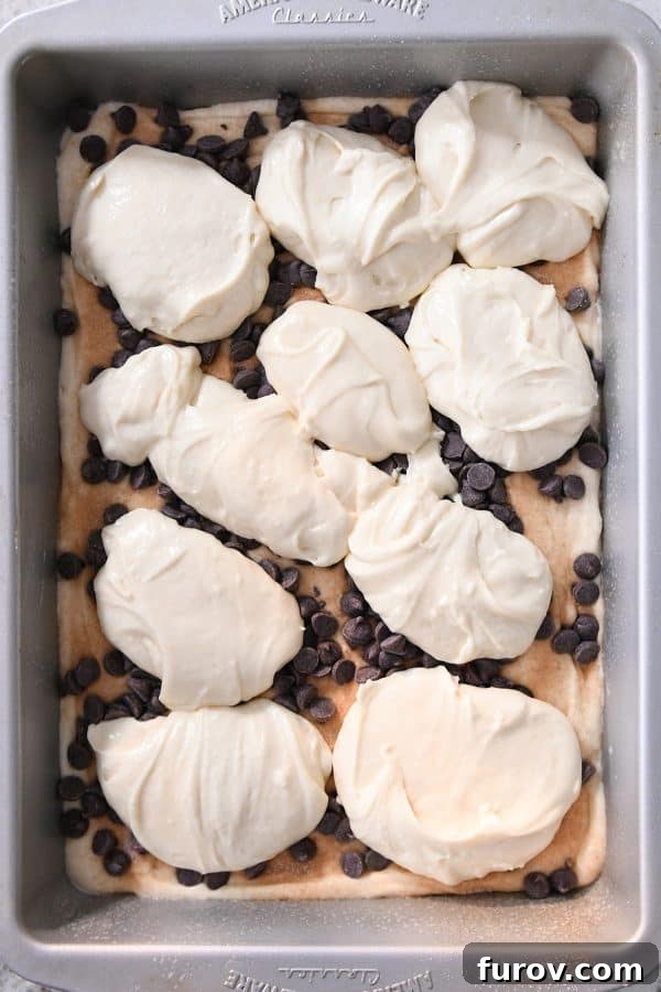 Large dollops of remaining cake batter spooned over the chocolate chips in a 9x13-inch pan, ready to be spread.