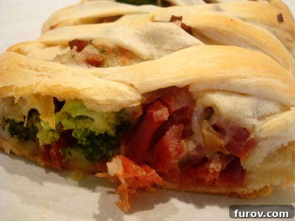 Close-up of a sliced cheesy ham and broccoli crescent braid, showing the creamy filling and golden crust.