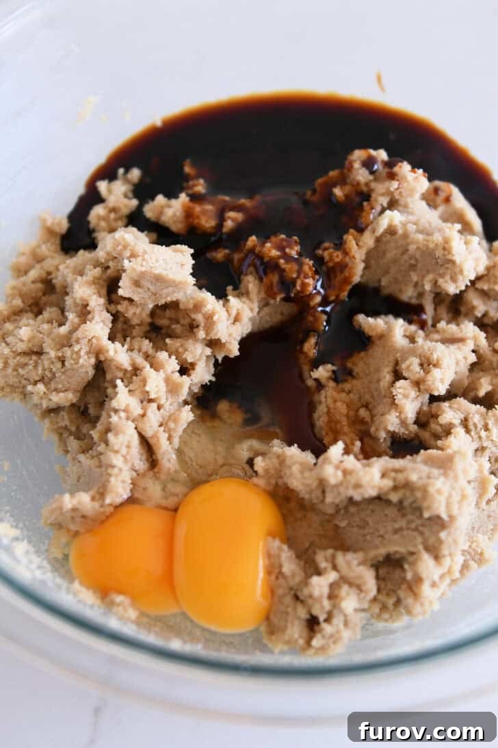 Glass bowl containing softened butter, brown sugar, granulated sugar, eggs, and rich molasses, ready for mixing.