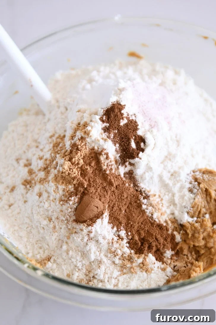 Glass bowl filled with dry ingredients: all-purpose flour, baking soda, aromatic cinnamon, ground ginger, salt, and cloves.