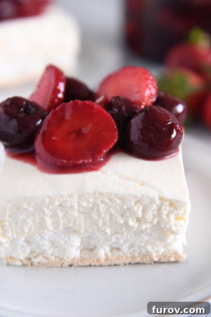A pristine slice of Berries on a Cloud dessert, perfectly layered with meringue, cheesecake, and a generous dollop of berry topping, presented on a clean white plate.