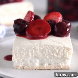 A piece of layered meringue dessert on a white plate topped with a berry sauce, ready to be served and enjoyed.