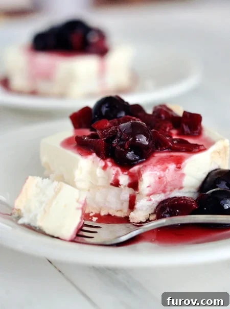 A close-up of a fork taking a bite out of the Berries on a Cloud dessert, highlighting its fluffy texture, distinct layers, and fresh berry topping.