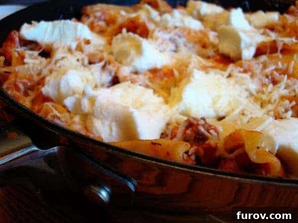 Hearty One-Pan Lasagna 2 A vibrant skillet full of perfectly cooked lasagna, generously topped with melted mozzarella and dollops of creamy ricotta cheese, ready to be served.