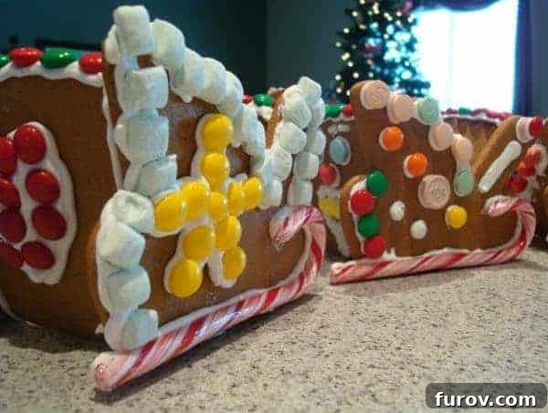 Two beautifully decorated gingerbread sleds with candy canes and other sweets on a kitchen countertop, evoking holiday cheer.