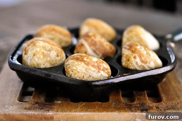 Side view of seven golden brown cooked ebelskiver's in an ebelskiver pan. Discover the magic of Danish ebelskivers with this step-by-step guide!