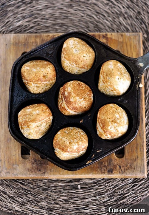 Top view of an ebelskiver pan with seven golden brown cooked ebelskivers in it. Essential equipment for making perfect Danish pancakes.