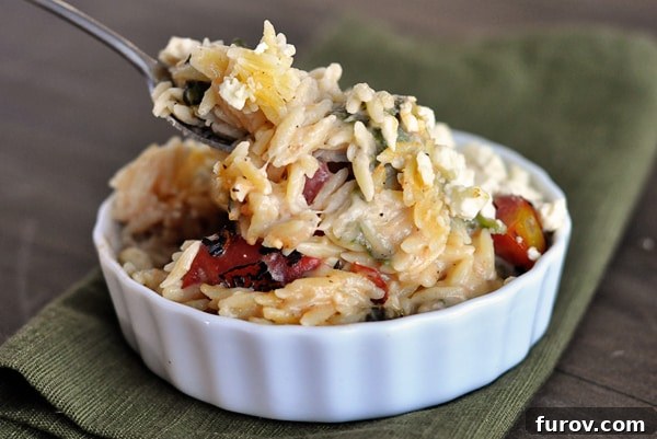 A small white ramekin filled with cooked cheesy orzo, beautifully presented and ready to be enjoyed.