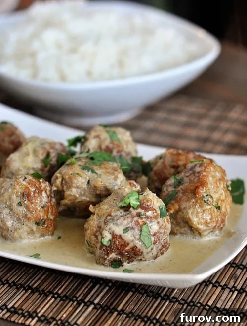 Vibrant Thai Green Curry Meatballs 3 Close-up of curry sauce and fresh parsley garnishing tender meatballs in a white serving dish, highlighting the vibrant green curry.