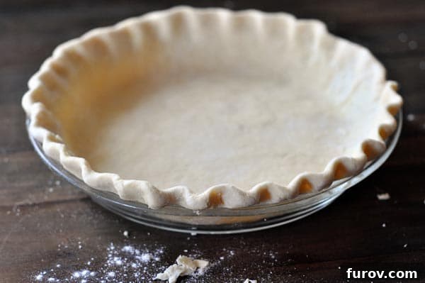 Uncooked crimped pie crust in a glass pie dish, ready for baking.