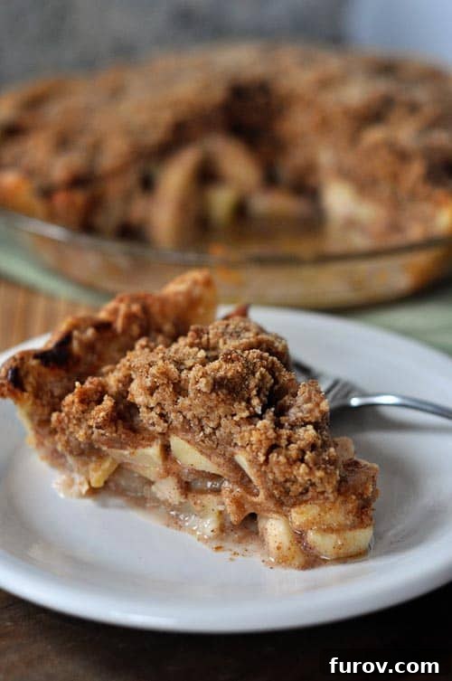 Spiced Orchard Apple Crumble 4 A beautifully baked apple crumb pie with one slice thoughtfully removed, sitting on a rustic wooden board, ready for serving.