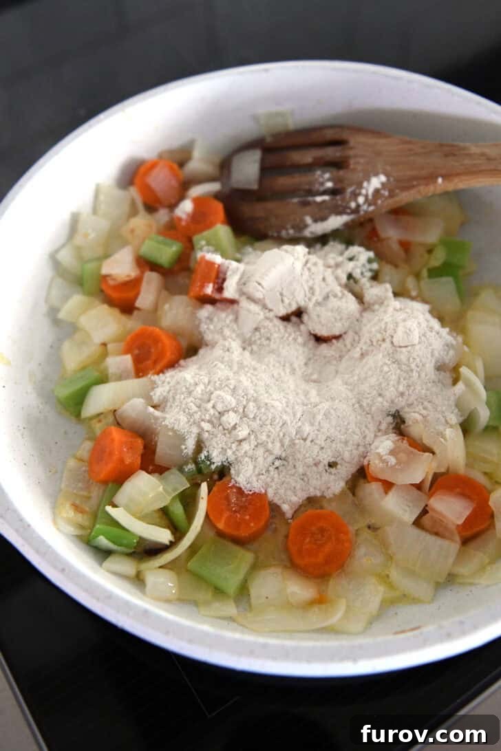 White skillet with flour, carrots, onions and celery.
