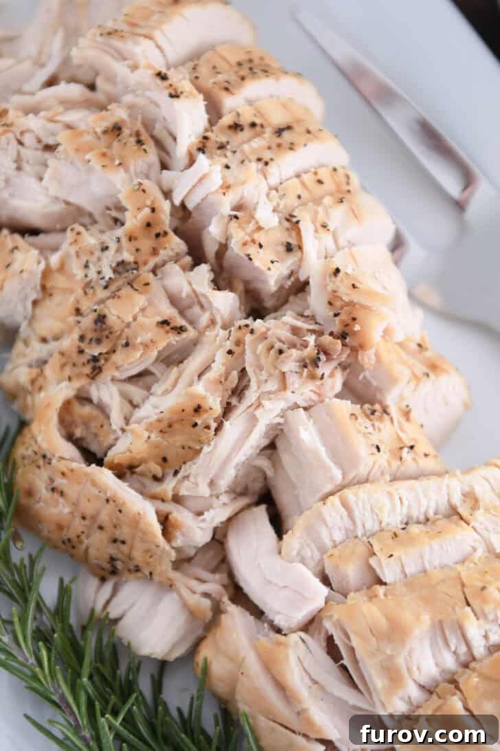 Top down view of cooked turkey breast slices on white platter.