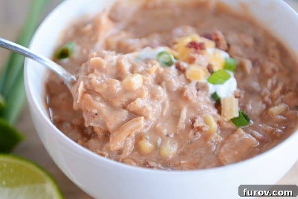A spoonful of rich and creamy jalapeno popper white bean chicken chili, showing its hearty texture and inviting warmth.
