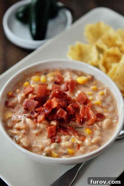 Top-down view of a delicious jalapeño white bean chili, beautifully garnished with crumbled crispy bacon.