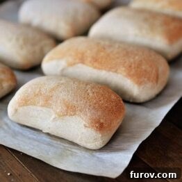 Mastering Chewy Italian Rolls 7 Golden brown chewy Italian rolls on a baking sheet, ready to be served.