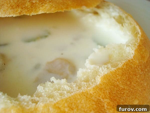 Rich and creamy Boston Clam Chowder served in a rustic homemade bread bowl, garnished with fresh herbs.