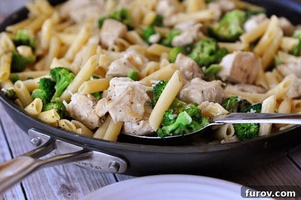 A skillet full of a chicken pasta and broccoli meal.