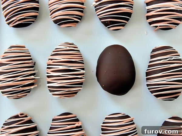 Top view of pink and white drizzled chocolate covered marshmallow eggs on a piece of parchment paper.