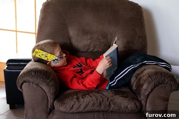 Saturday Survival: Mastering Summer Break 4 A young boy is engrossed in reading a book, sitting comfortably on a brown recliner, illustrating a peaceful and educational summer activity.