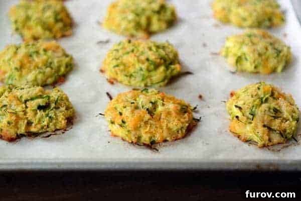 Four golden-brown Baked Cheesy Zucchini Bites, stacked appealingly on a white ramekin, ready to be served and enjoyed.
