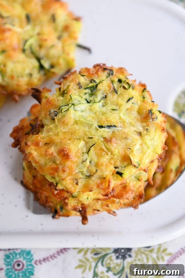 A top-down view of a delightful stack of baked cheesy zucchini bites, golden and inviting, ready to be enjoyed as a perfect summer snack or side.