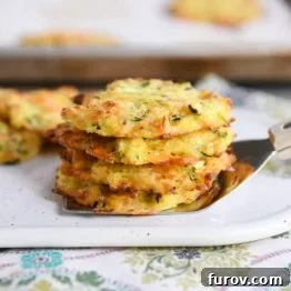 Cheesy baked zucchini bites stacked on a spatula, showcasing their golden-brown color and appealing texture.