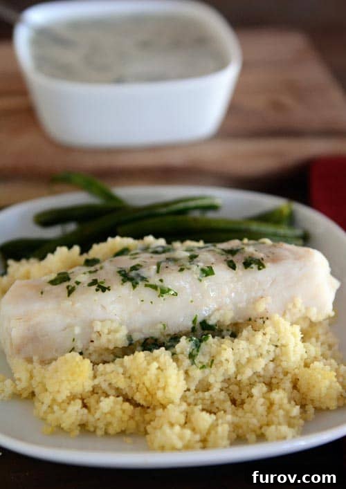 Make-Ahead Thai Fish and Creamy Couscous Packets 2 A white plate with cooked couscous topped with a cooked fish fillet, vibrant green beans, and a generous drizzle of creamy Thai-style coconut sauce. This visually appealing meal highlights the healthy and delicious aspect of the make-ahead Thai-style fish and couscous packets, ready to be enjoyed as a gourmet foil dinner.