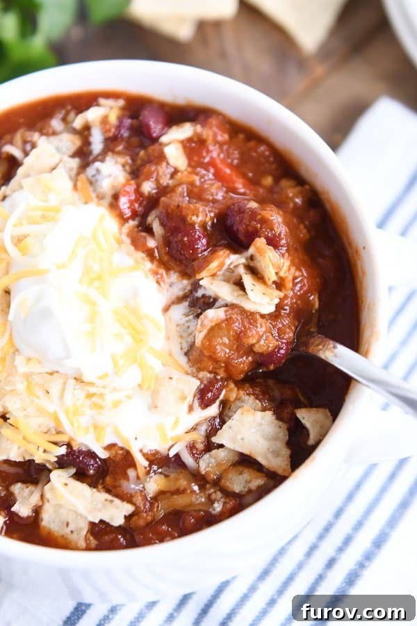 Slow-Simmered Comfort Chili 3 Top down view of classic slow cooker chili in white bowl with cheese and sour cream.