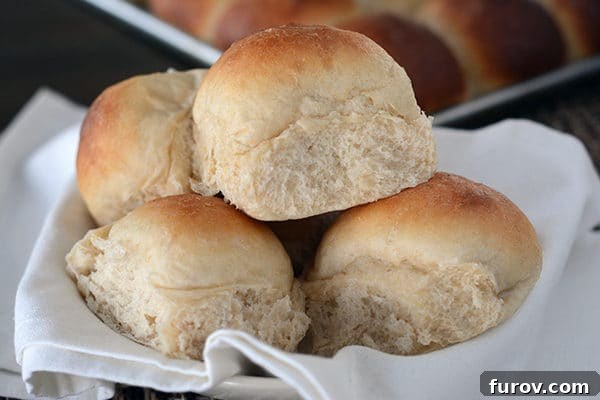 The Ultimate Cloud-Soft Buttermilk Potato Rolls 3 A generous pile of freshly baked, golden-brown buttermilk potato rolls arranged artfully on a white linen napkin, exuding warmth and inviting aroma.