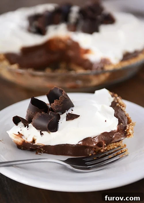 Salty Sweet Chocolate Pretzel Pie 3 A perfectly portioned slice of chocolate pudding pretzel pie on a white plate, showcasing the distinct layers against the backdrop of the whole pie.