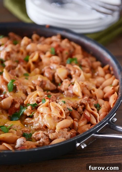 A skillet full of a vibrant taco pasta shell dinner, richly topped with melted cheese, ready to be served.