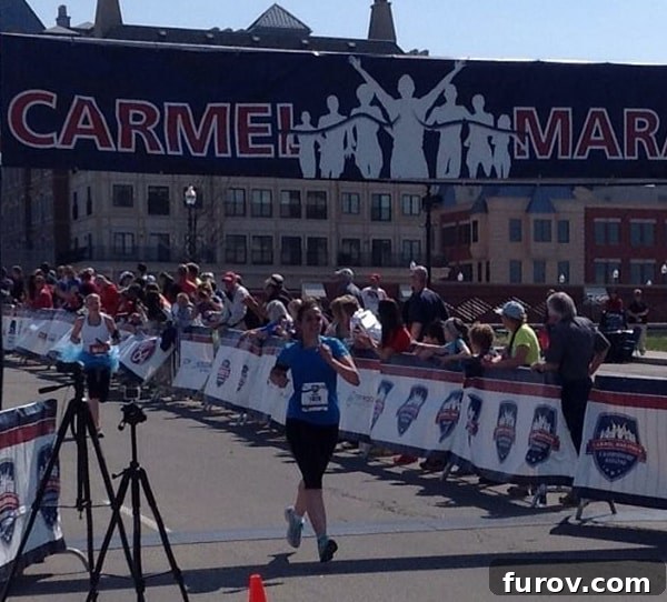 A woman in vibrant running gear with a determined expression, crossing the finish line, symbolizing accomplishment and strength.