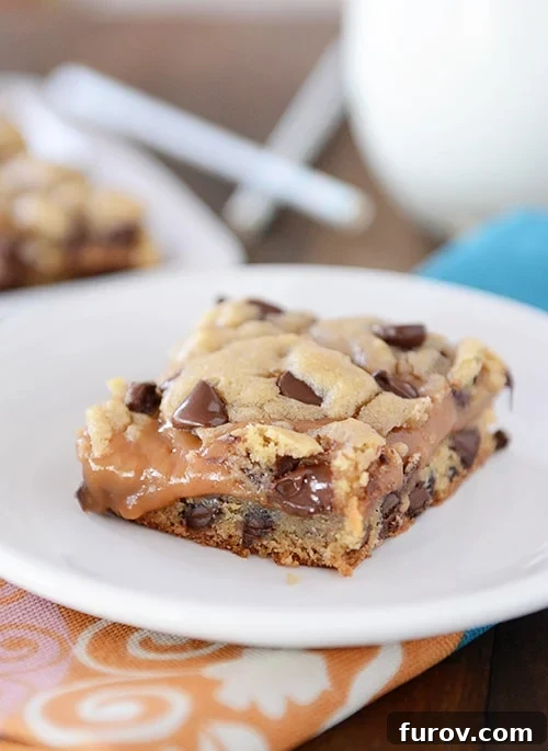 A chocolate chip peanut butter caramel cookie bar on a white plate, showcasing its rich layers and tempting texture.