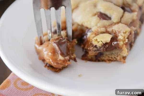 A fork taking a generous bite out of a Peanut Butter Caramel Cookie Bar, revealing its soft interior and gooey center.