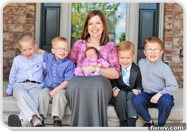 A heartwarming family portrait featuring a woman cradling a small baby girl, surrounded by four joyful young boys.