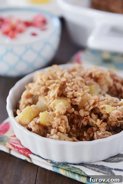 Old-Fashioned Apple Cinnamon Baked Oats 2 A small white bowl of baked oatmeal with chunks of cinnamon-coated apples.