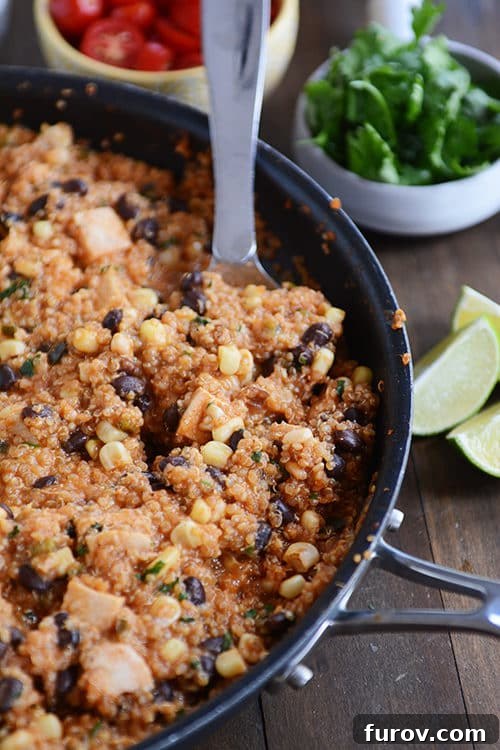 Effortless One-Pan Quinoa Enchiladas 2 A large metal spoon taking a generous helping of a colorful quinoa enchilada black bean meal out of a rustic skillet, showcasing the rich textures and vibrant ingredients.