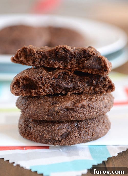 Decadent Greek Yogurt Double Chocolate Cookies 2 A stack of rich double chocolate Greek yogurt cookies with the top cookie split in half, revealing its soft, chewy interior.