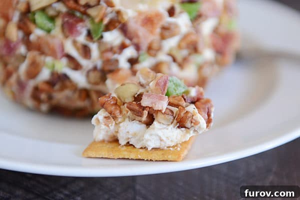 A crispy cracker generously topped with the creamy, rich bacon jalapeno popper cheeseball, ready for a delectable bite.