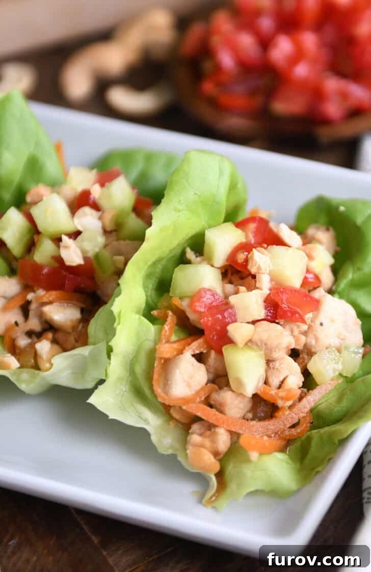 Top down view of lettuce leaves full of a chicken vegetable mixture on a white plate.