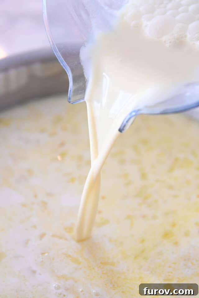 Pouring milk and flour mixture into saucepan with onions and garlic, beginning the gravy creation.