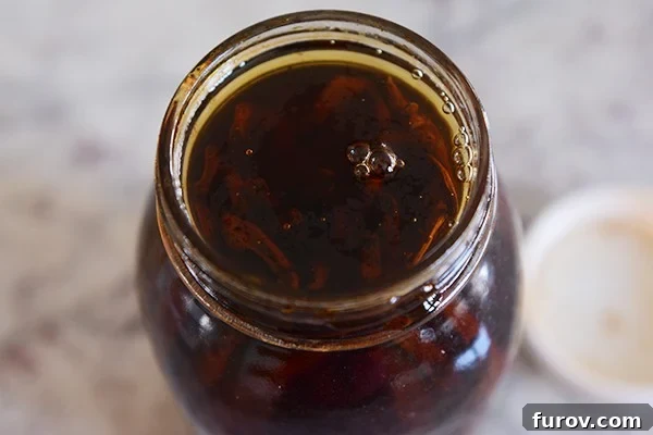 Top view of a mason jar full of alcohol-soaked vanilla beans.