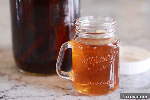 Homemade vanilla extract in a glass mug.