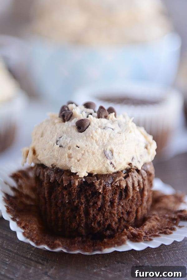 Double Fudge Brownie Cupcakes 2 An unwrapped chocolate cupcake with a thick layer of cookie dough frosting on top, showcasing its rich texture.