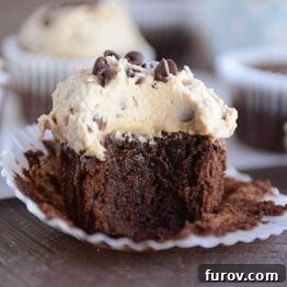 A chocolate cupcake with a thick layer of frosting and a bite taken out, perfect for a recipe card.