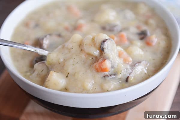 A spoon taking a bite out of a creamy mushroom and potato soup, showcasing its rich texture.