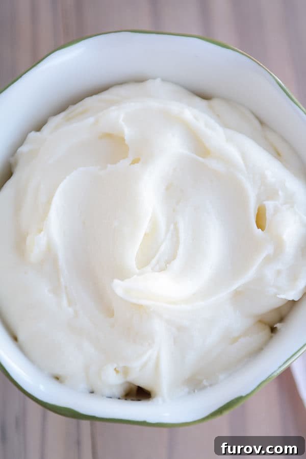A beautiful top-down view of a large bowl filled with perfectly whipped, creamy vanilla buttercream frosting, showcasing its smooth texture and readiness for use.